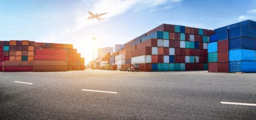 Shipping yard with stacked colorful cargo containers and a plane taking off in a bright blue sky