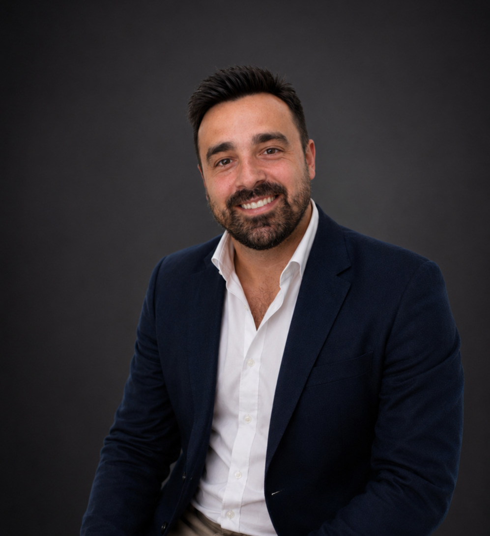 Javier Hidalgo - RRHH - IP | Negocios10.Com Portrait of a smiling man in a navy blazer and white shirt against a dark studio backdrop.