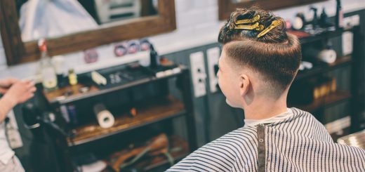 Customer sits in a barber chair with a freshly trimmed undercut, mirrors and barber station in the background.