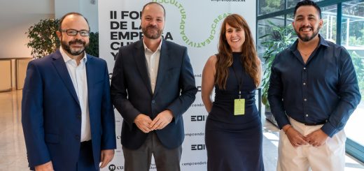 Four professionals posing for a group photo at a conference, standing in front of a banner with event branding.