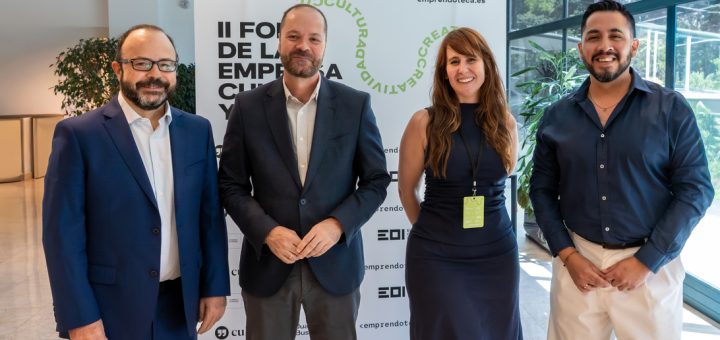 Four professionals posing for a group photo at a conference, standing in front of a banner with event branding.
