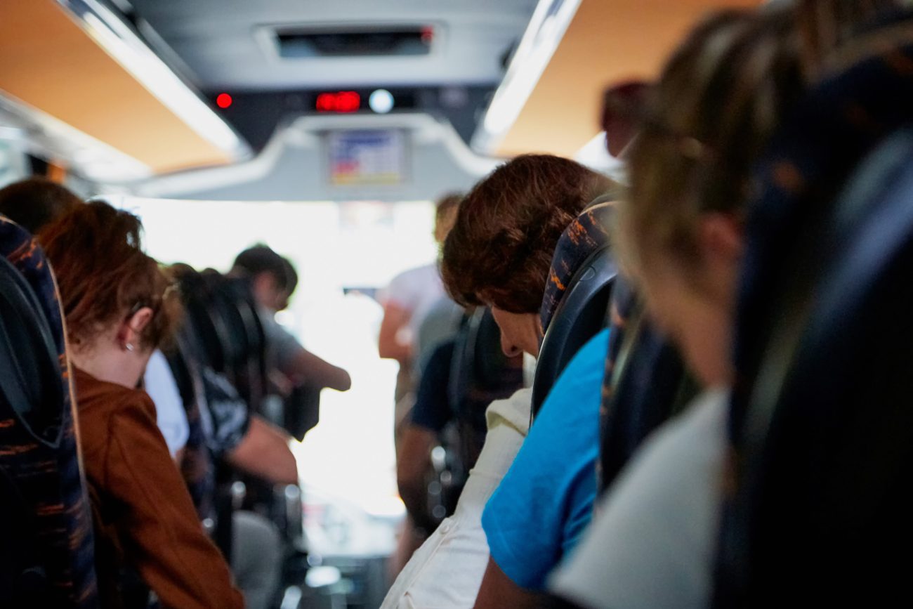 777469 Autocares Font | Negocios10.Com Interior of a crowded bus with passengers seated along both sides of the aisle, seen from the middle.”,