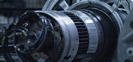 Large industrial turbine component with circular metal sections and attached cables in a workshop.