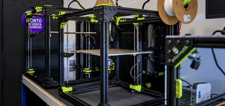 Lab 3D printer inside a black frame with neon-green components and spool holders on top.